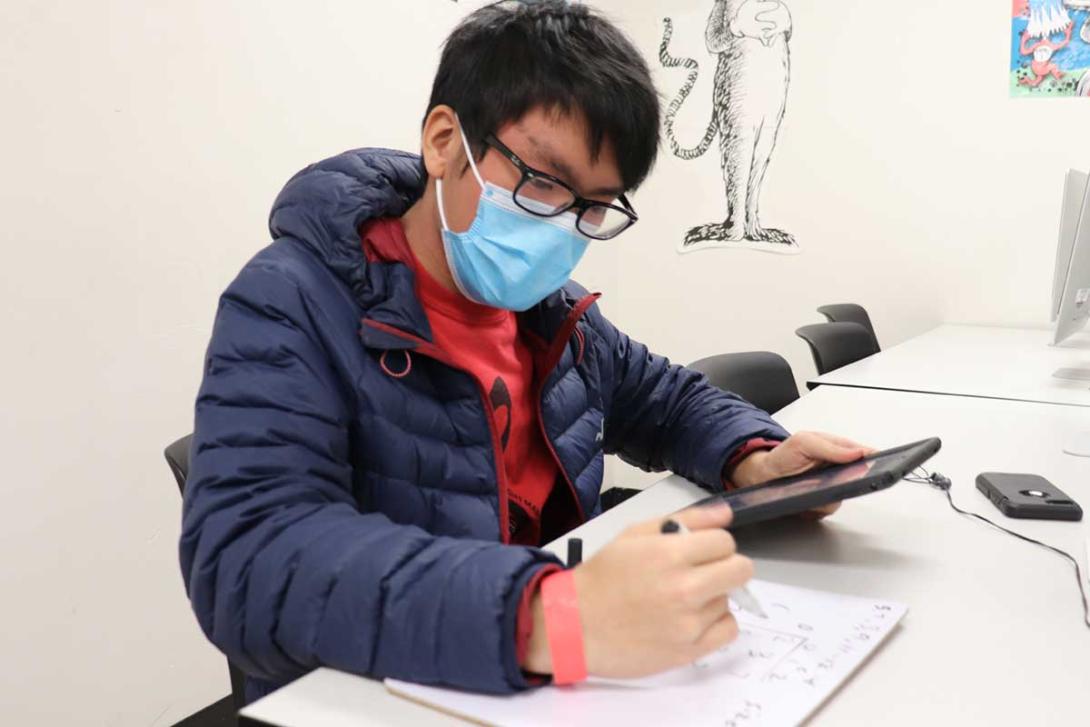 High school boy using iPad as reference for class assignment.