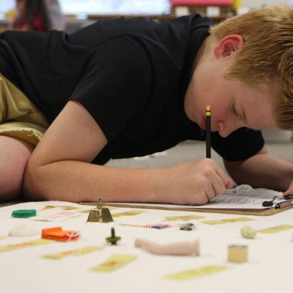 Montessori boy working on drawing on the floor.