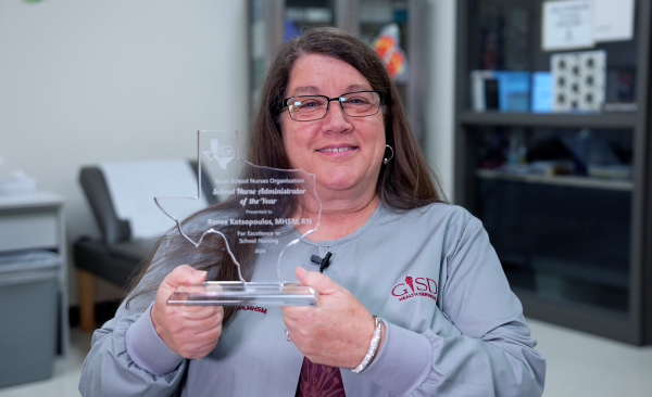 Nurse K smiles while holding a glass Texas-shaped award reading "TSNO School Nurse Administrator of the Year".